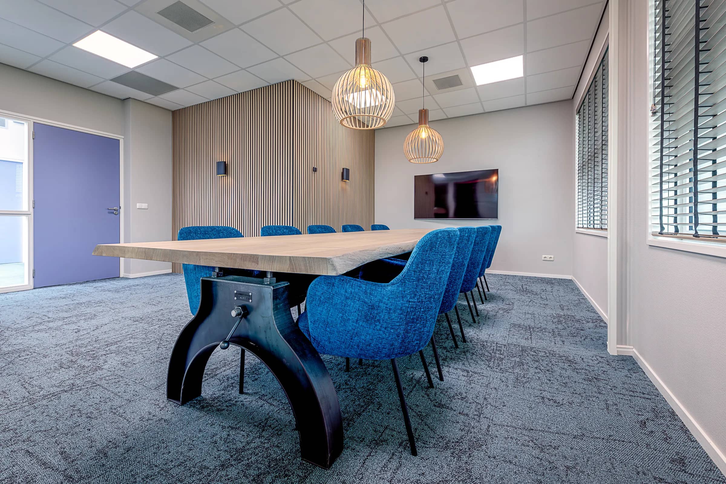 Meeting room with a long table, blue chairs and a wall screen at Wiz Arts
