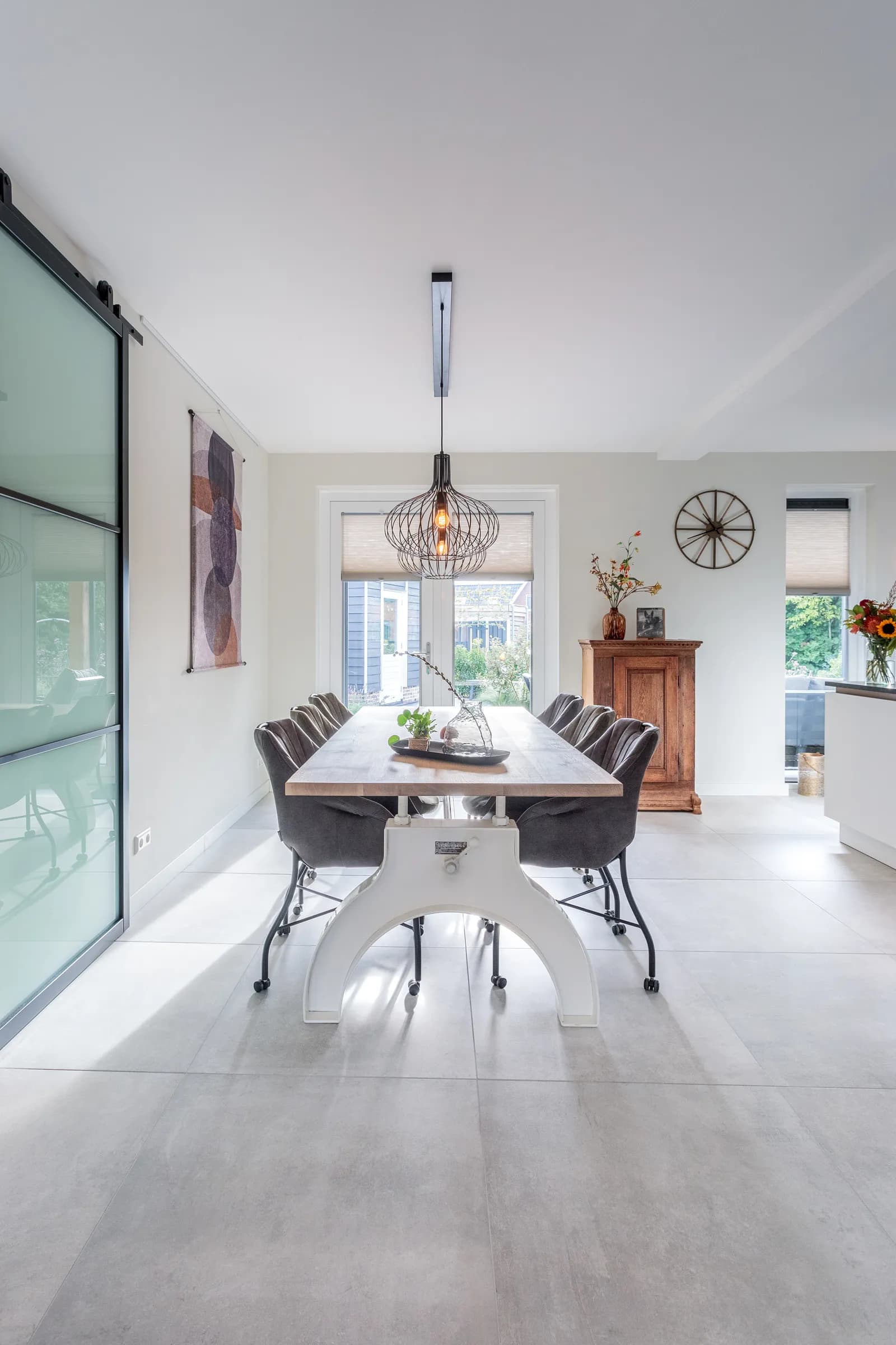 Oak dining table on a white steel column base with a pendant lamp and wall clock in the Loosman family home