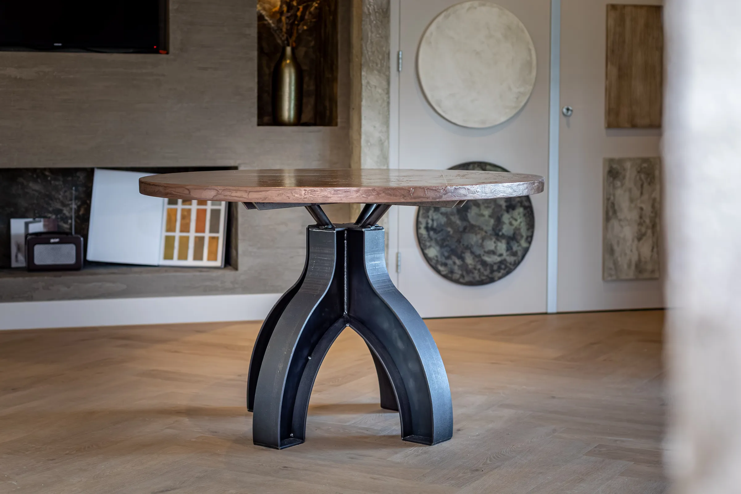 Round oak table on a black double arch base with a chair, seen up close