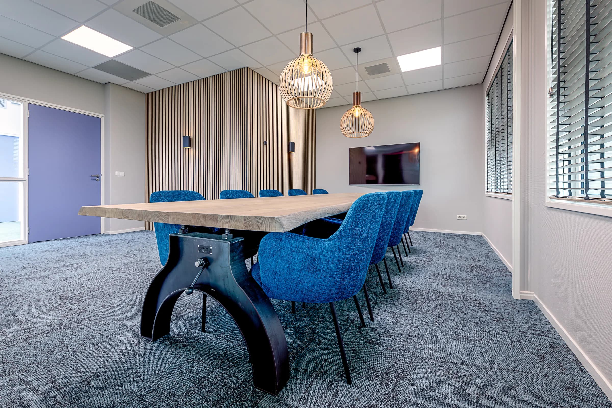 Meeting room with a long table, blue chairs and a wall screen at Wiz Arts