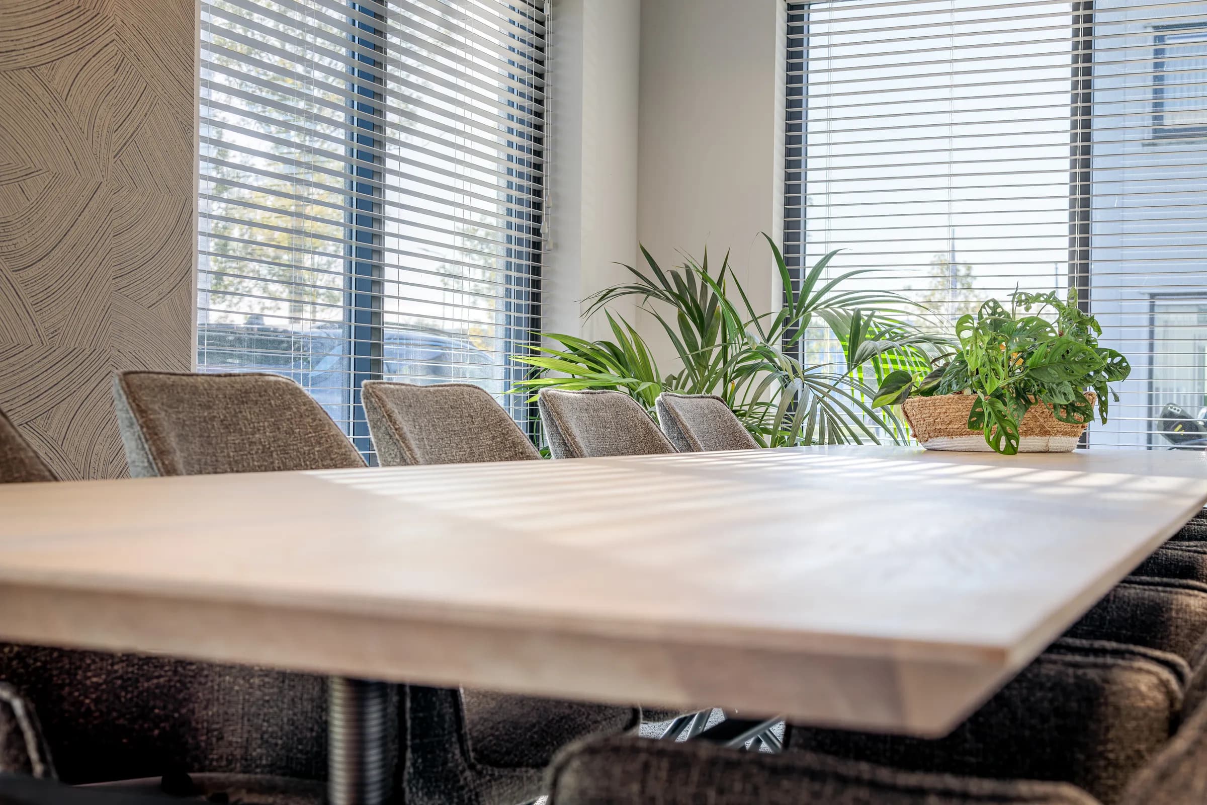 Light oak table top and grey chairs up close in the Advies en Kies office