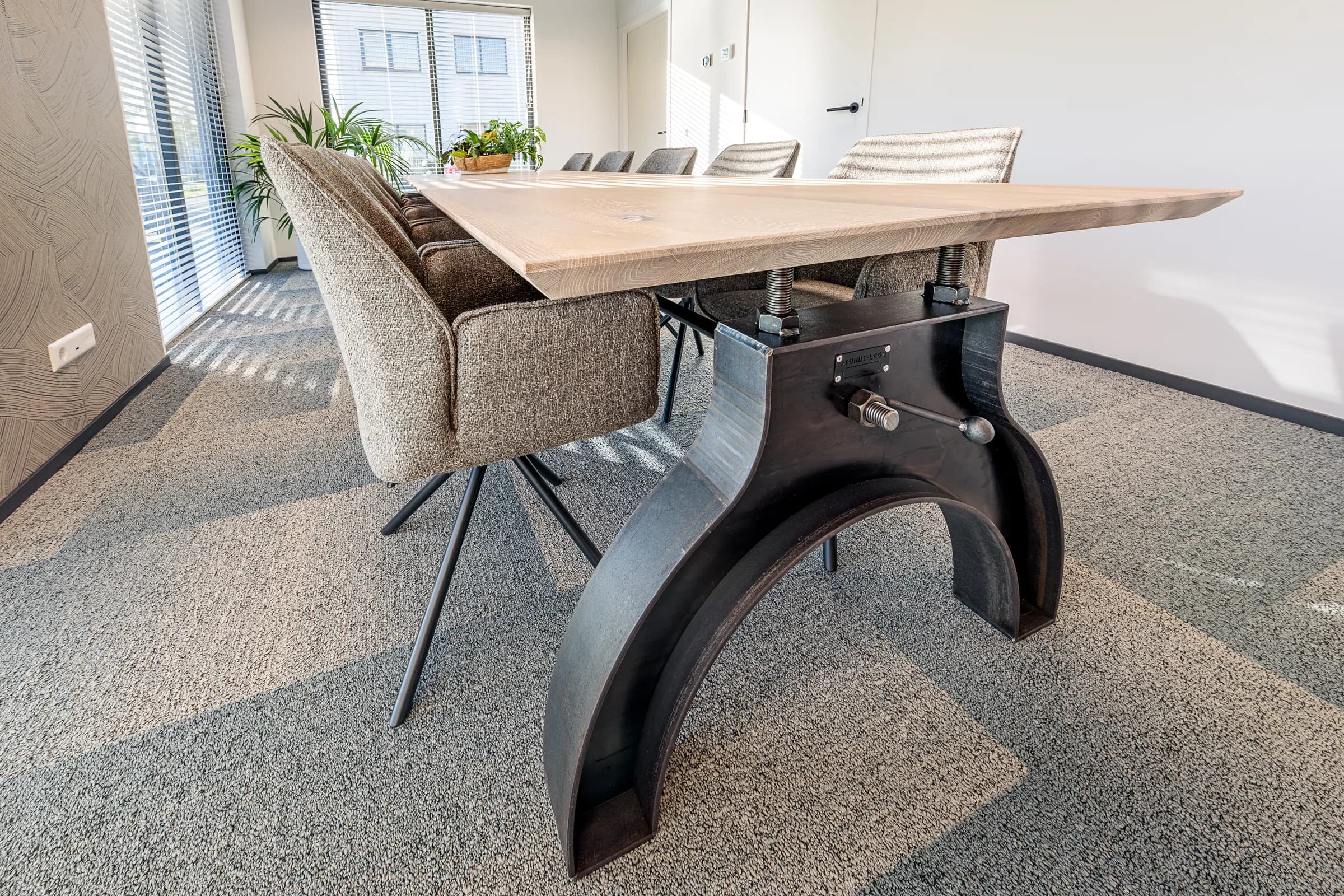 Side view of a light oak table on a black cast iron column base in the Advies en Kies office